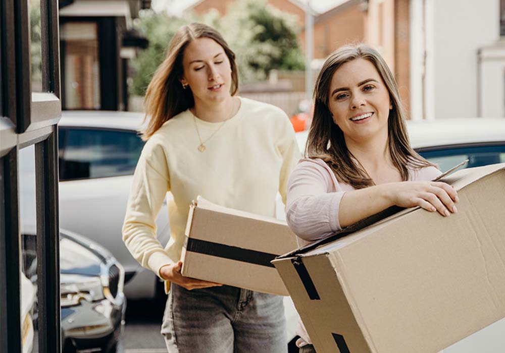 Two people carrying moving boxes