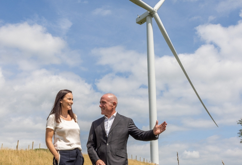 business people talking next to a wind turbine