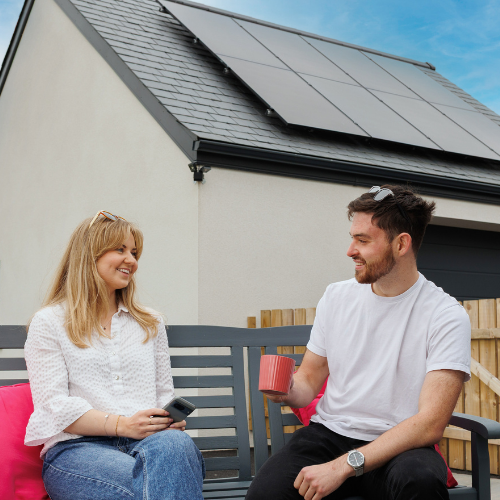 man and woman sitting on bench with solar panels behind them